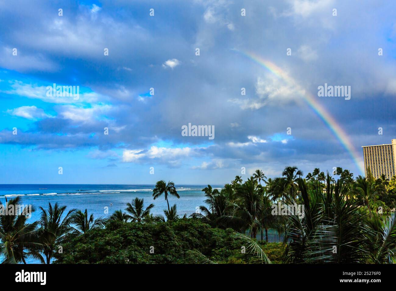Ein Regenbogen ist am Himmel über einem Strand zu sehen. Der Himmel ist bewölkt und das Meer ist im Hintergrund Stockfoto