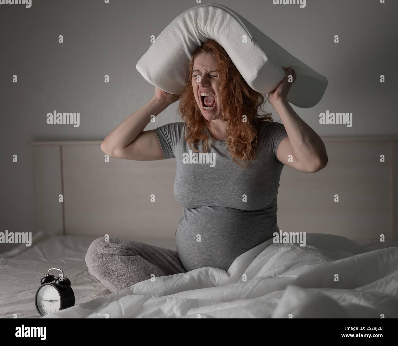 Kaukasische Schwangere sitzend und schreiend, während sie an Schlaflosigkeit litt. Stockfoto