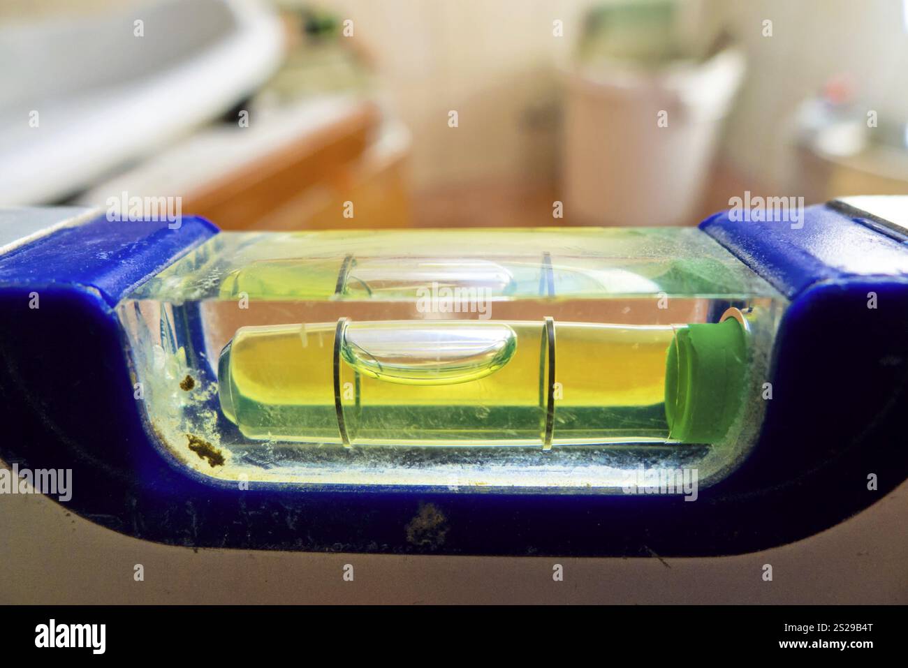 Eine Wasserwaage weist Ungenauigkeiten auf. Renovierung und Renovierung eines Badezimmers. Symbolisches Foto für verpfuschte Konstruktion Stockfoto