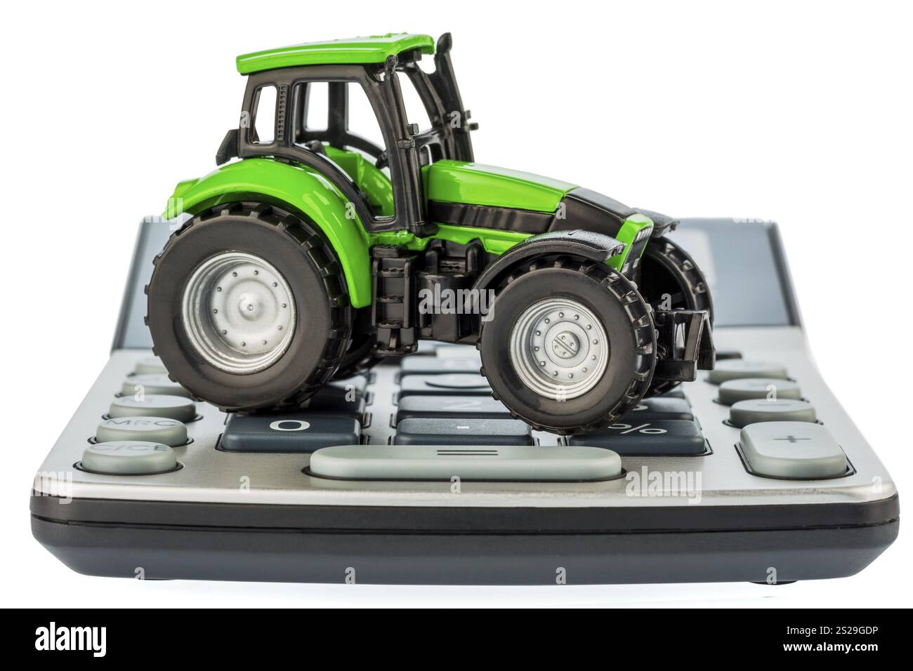 Ein Traktor liegt auf einem Rechner. Kosten für Benzin, Verschleiß und Versicherung. Kosten und Subventionen in der Landwirtschaft Stockfoto