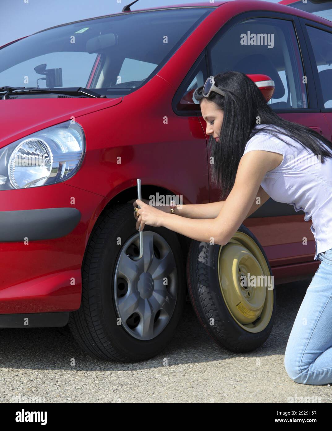 Eine junge Frau mit einem Platten Reifen auf ihrem Auto Stockfoto