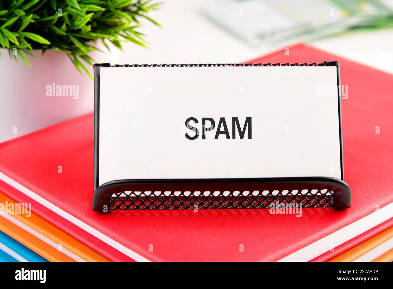 Ein klares Spam-Schild befindet sich auf einem Schreibtisch zwischen lebendigen Ordnern und einer Büroanlage, das einen übersichtlichen Arbeitsplatz ohne Kabelgewirr hervorhebt. Die Einstellung entspricht o Stockfoto