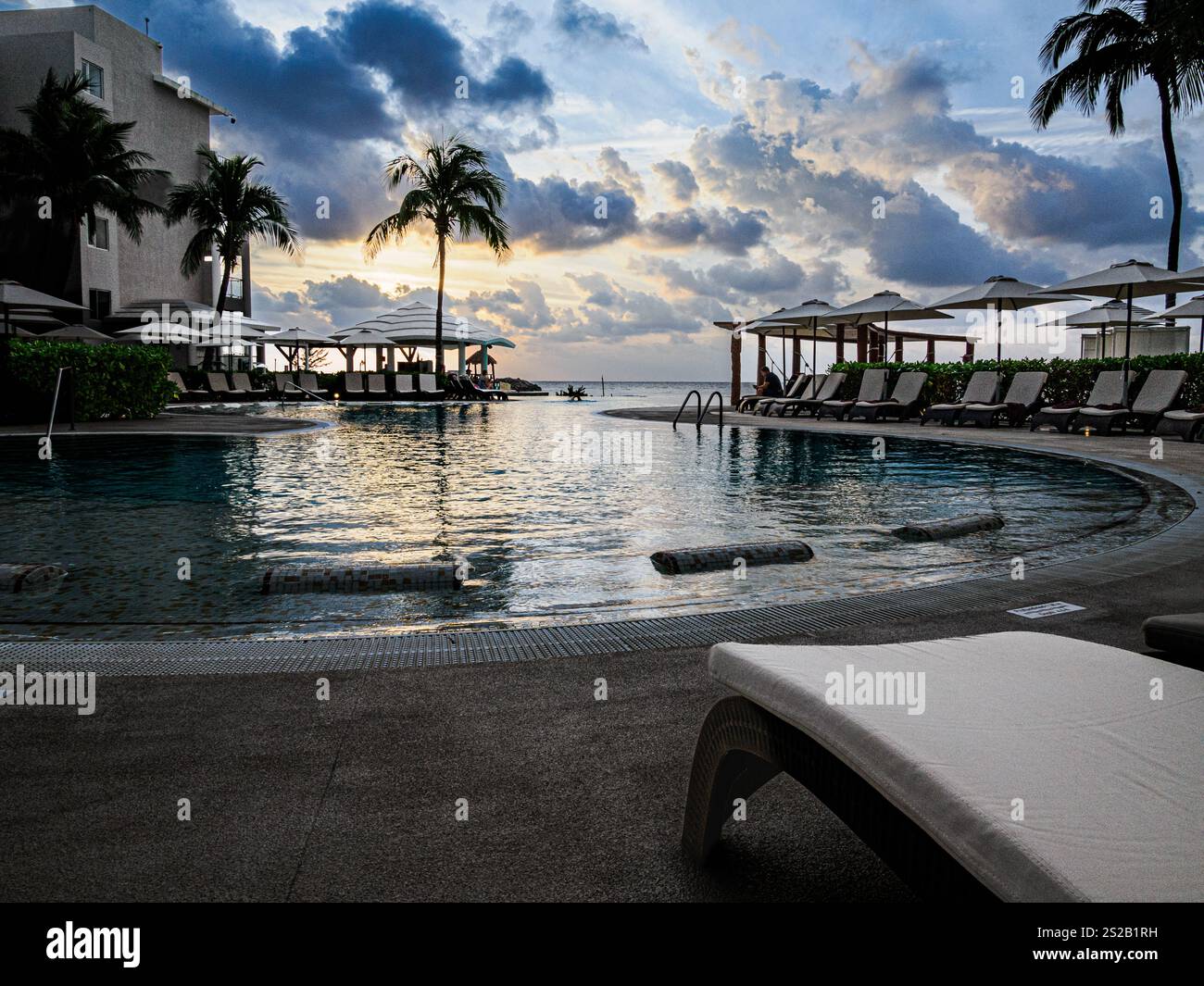 Ein Infinity-Pool erstreckt sich ruhig zum Horizont kurz vor Sonnenaufgang Stockfoto