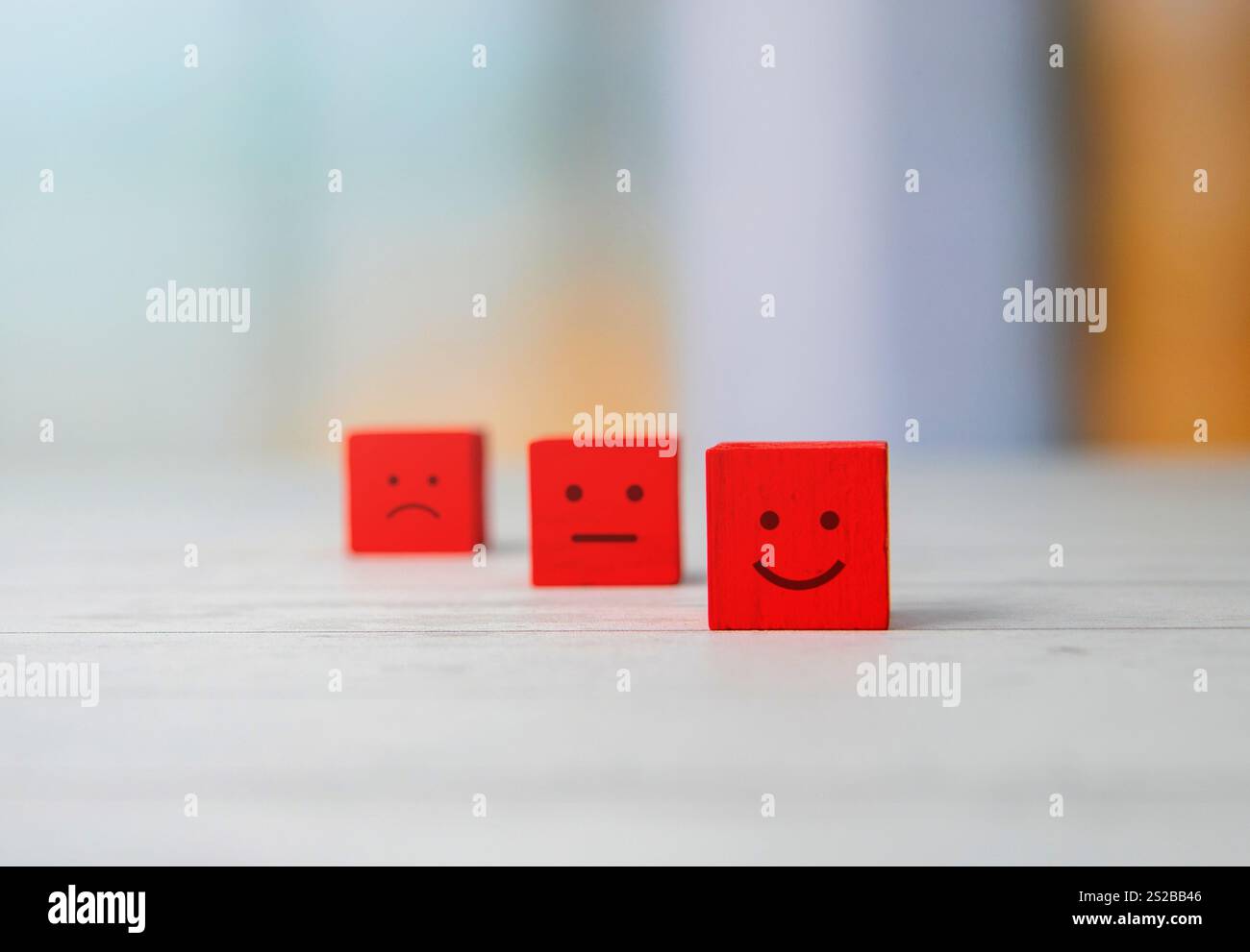 Holzblöcke mit Gesichtsausdrücken traurig, neutral und glücklich. Kundenzufriedenheit, Feedback und Emotionskonzept. Stockfoto