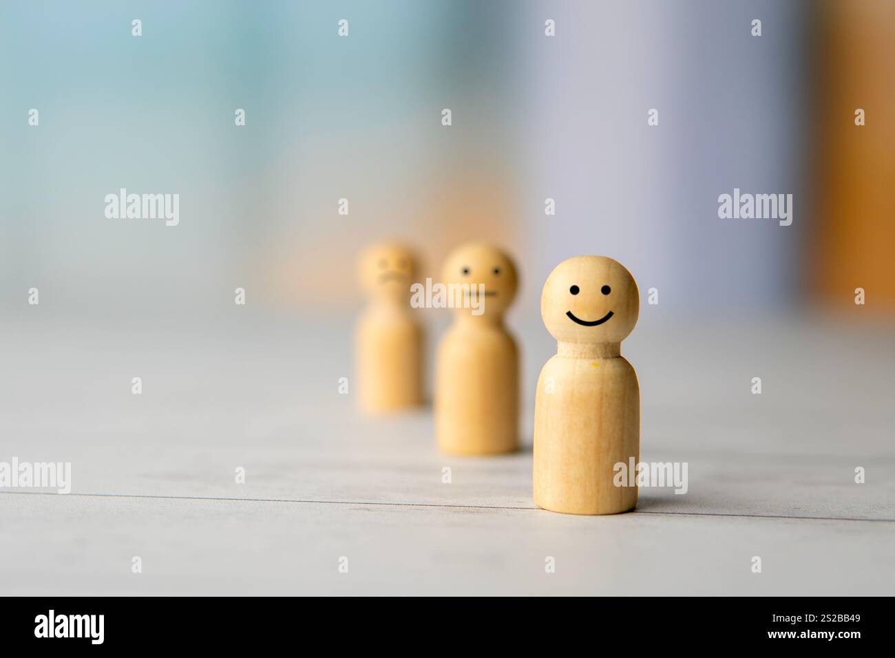 Drei Holzfiguren stehen in einer Reihe mit einem anderen Gesichtsausdruck. Emotionen, Glück und positives Denken. Stockfoto