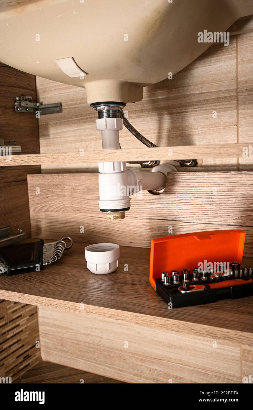 Der Klempner arbeitet mit Werkzeugen und Bauteilen an Abflussrohren für Waschbecken, um einen effizienten Wasserfluss zu gewährleisten und Probleme mit der Rohrleitung zu lösen. Stockfoto