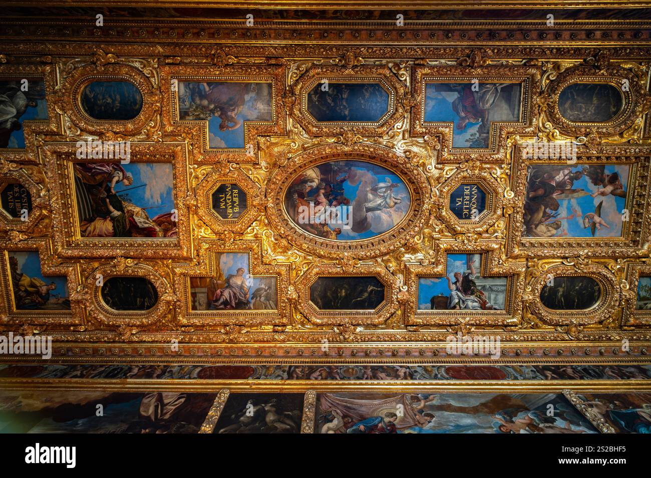 Eine opulente Decke mit vergoldeten Rahmen, kunstvollen Schnitzereien und lebendigen Fresken, die mythologische und allegorische Szenen in einer Geschichte darstellen Stockfoto