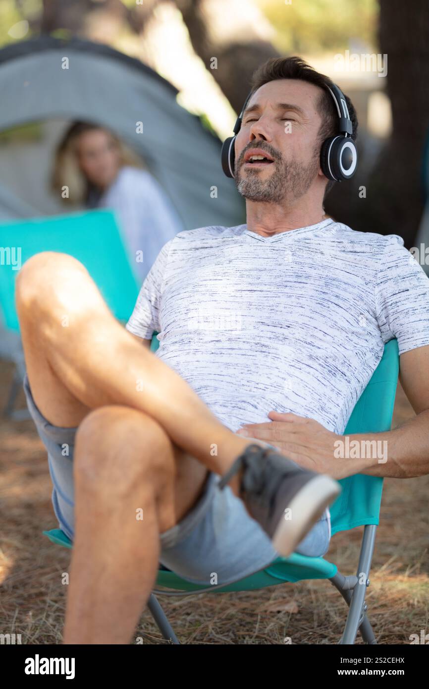 Hübscher junger Mann, der im Camping Musik in Kopfhörern hört Stockfoto