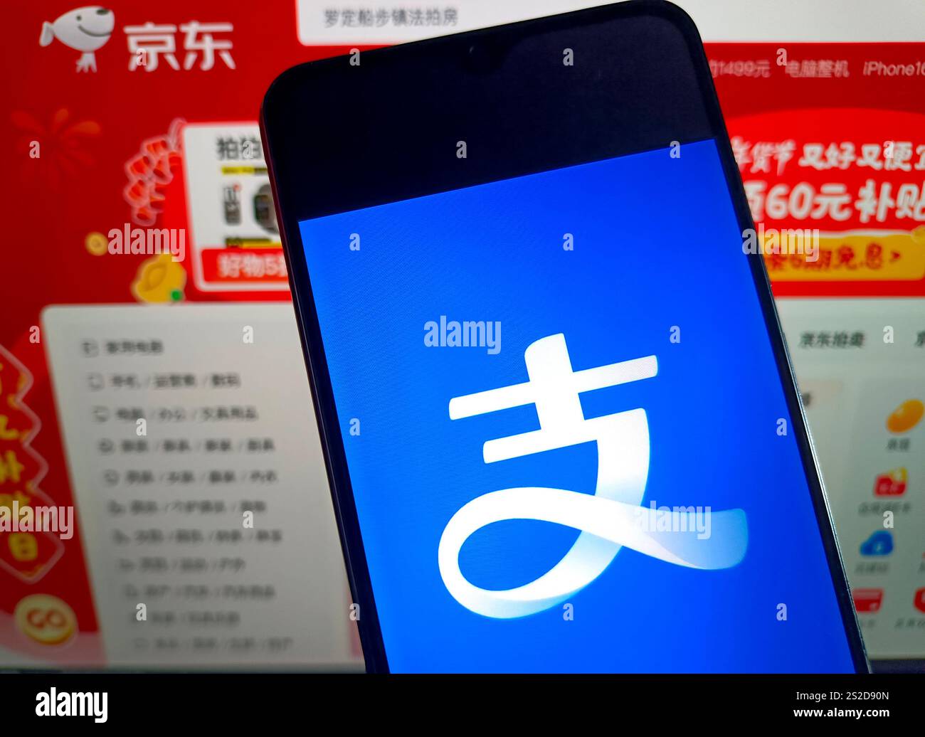 SUQIAN, CHINA - 7. JANUAR 2025 - eine Illustration zeigt Alipay auf einem Mobiltelefon im Hintergrund von JD.com's Seite, Suqian, Provinz Jiangsu, China, Stockfoto