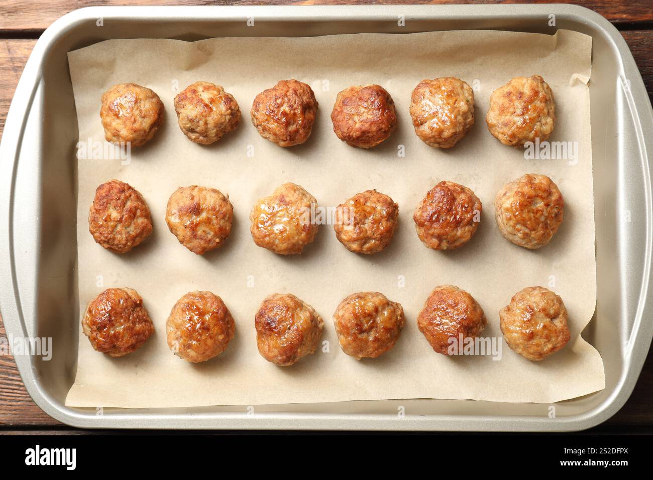 Viele leckere Fleischbällchen in der Auflaufform auf Holztisch, Blick von oben Stockfoto