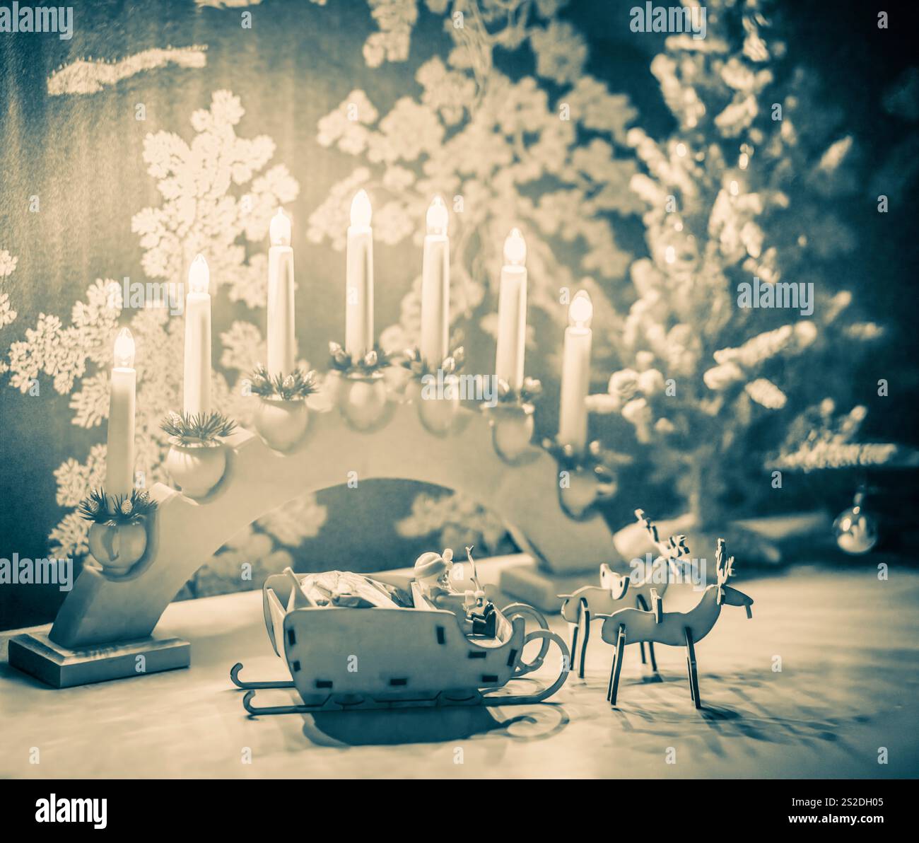 Festliche Weihnachtsszene mit lasergeschnittenem MDF-Schlitten und Rentieren mit Kerzenlichtern. Stockfoto