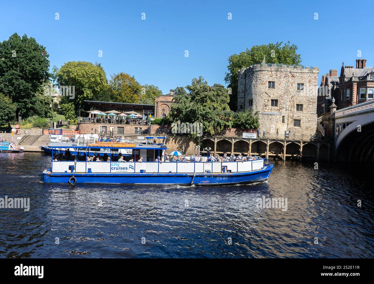 Sightseeing-Boot nähert sich der Lendal Bridge auf dem Fluss Ouse, York, North Yorkshire mit Lendal Tower im Hintergrund Stockfoto