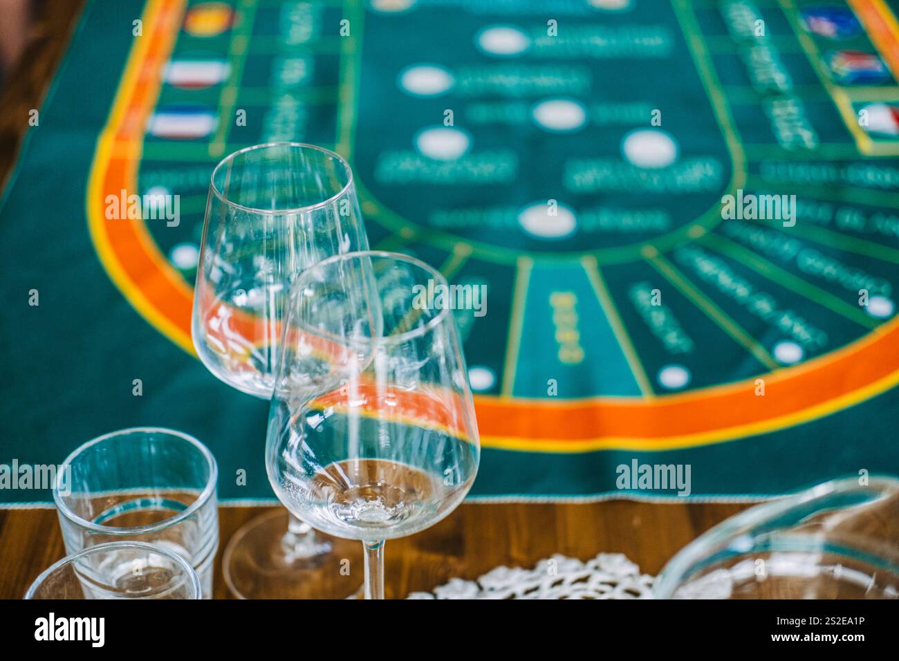 Nahaufnahme leerer Weingläser auf einem Tisch mit einer Kasino-Matte im Weinstil, die Luxus und Unterhaltung verbindet Stockfoto