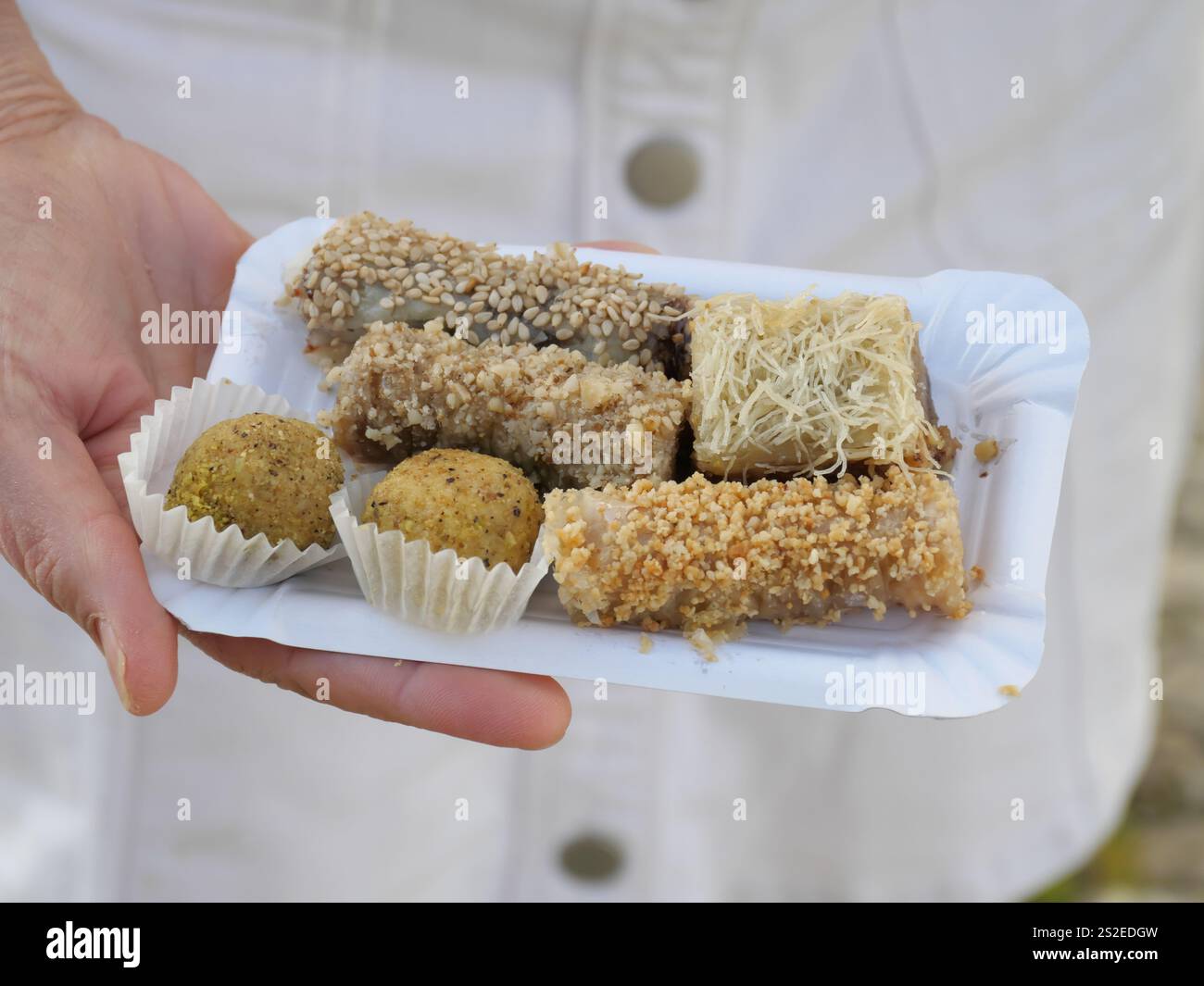 Eine Hand präsentiert süße Bonbons, gerollt in Kokosflocken von einem Straßenhändler in Ronda, Spanien Stockfoto