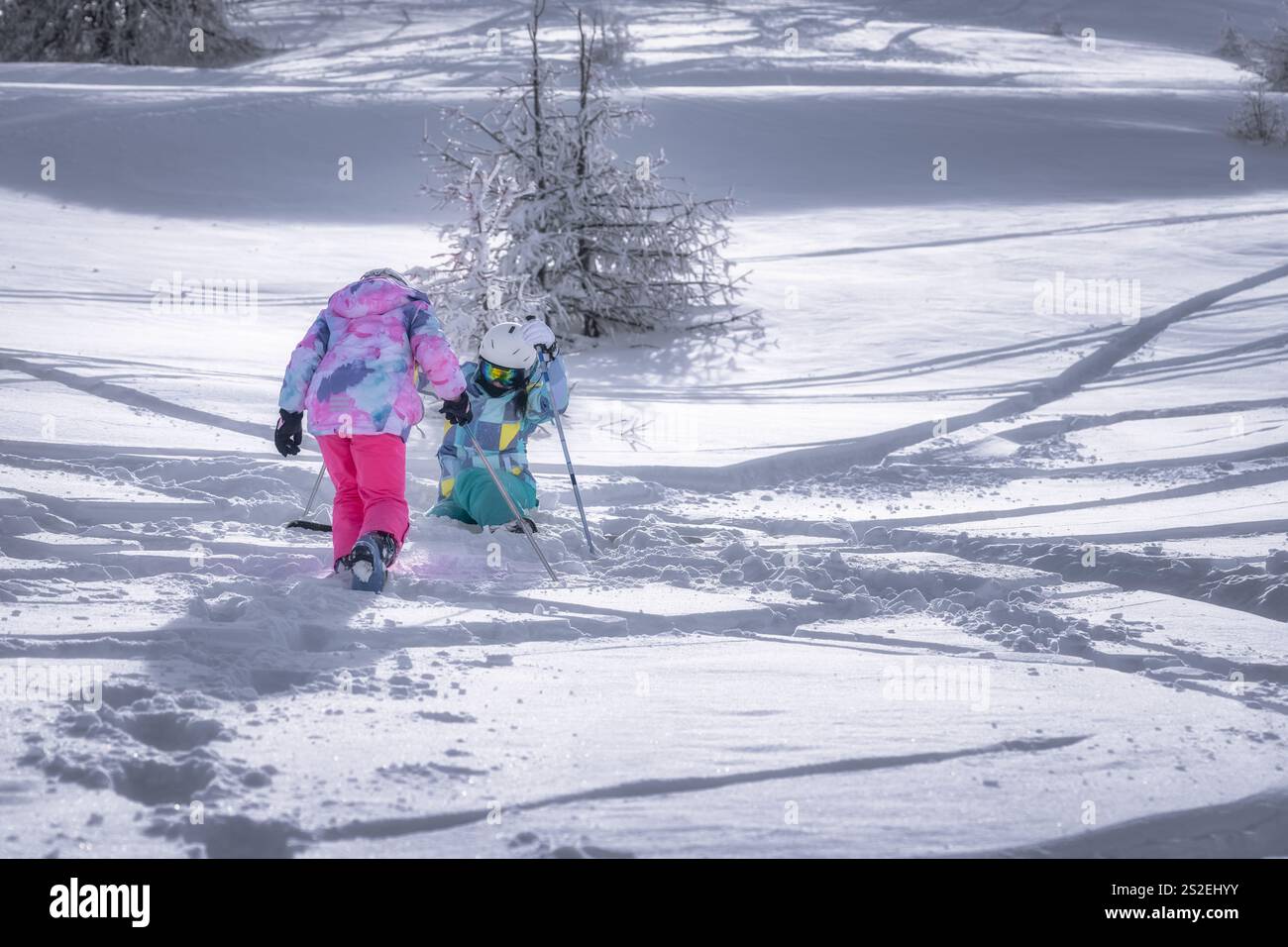 Mutter und Tochter begeben sich auf ein aufregendes, schneebedecktes Abenteuer, gekleidet in farbenfrohe und helle Winterkleidung, die schöne Erinnerungen vor einem Bild schaffen Stockfoto