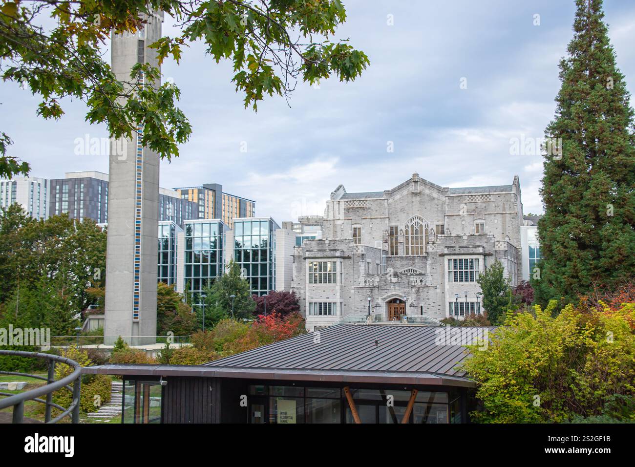 Malerischer Blick auf das Irving K. Barber Learning Centre von UBC mit gotischer Architektur, einem hohen Uhrenturm, modernen Glasgebäuden und üppigem Grün. Stockfoto