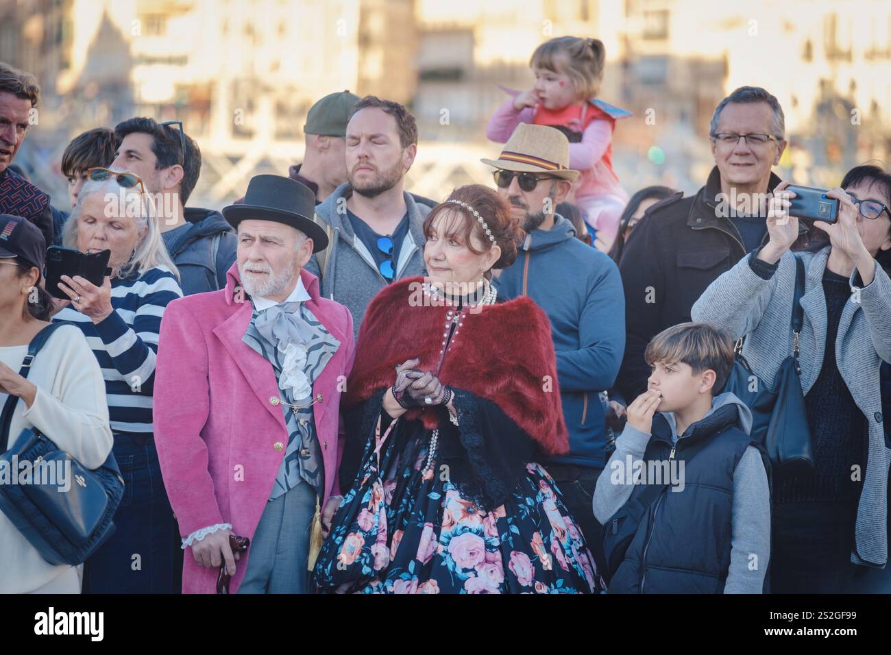 Das Bild zeigt eine Gruppe von Personen, die bei einer Veranstaltung oder einem Ort im Freien als Zuschauer oder Touristen erscheinen. Ihre Aufmerksamkeit scheint sich auf etwas zu konzentrieren Stockfoto