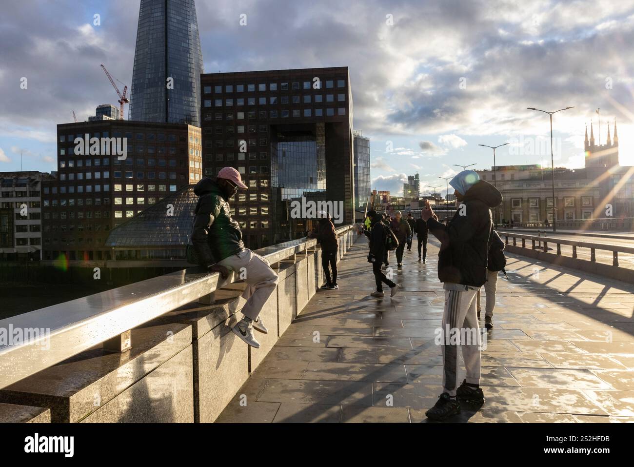 Wintertouristen genießen die Sonne am späten Nachmittag auf der London Bridge nach sintflutartigen Regenfällen über die Hauptstadt an einem kalten Wintertag in London, England. Stockfoto