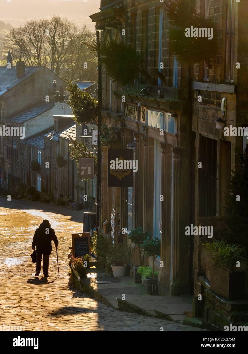 Main Street in Haworth an einem sonnigen Wintertag mit einer Silhouette in der Ferne. West Yorkshire, Großbritannien. Stockfoto