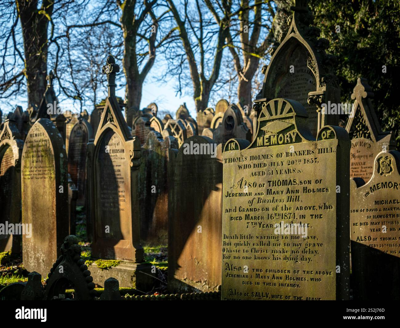 Grabsteine auf dem sonnendurchfluteten Friedhof der St. Michael All Angels Church in Haworth, Bronte Country, West Yorkshire. UK Stockfoto
