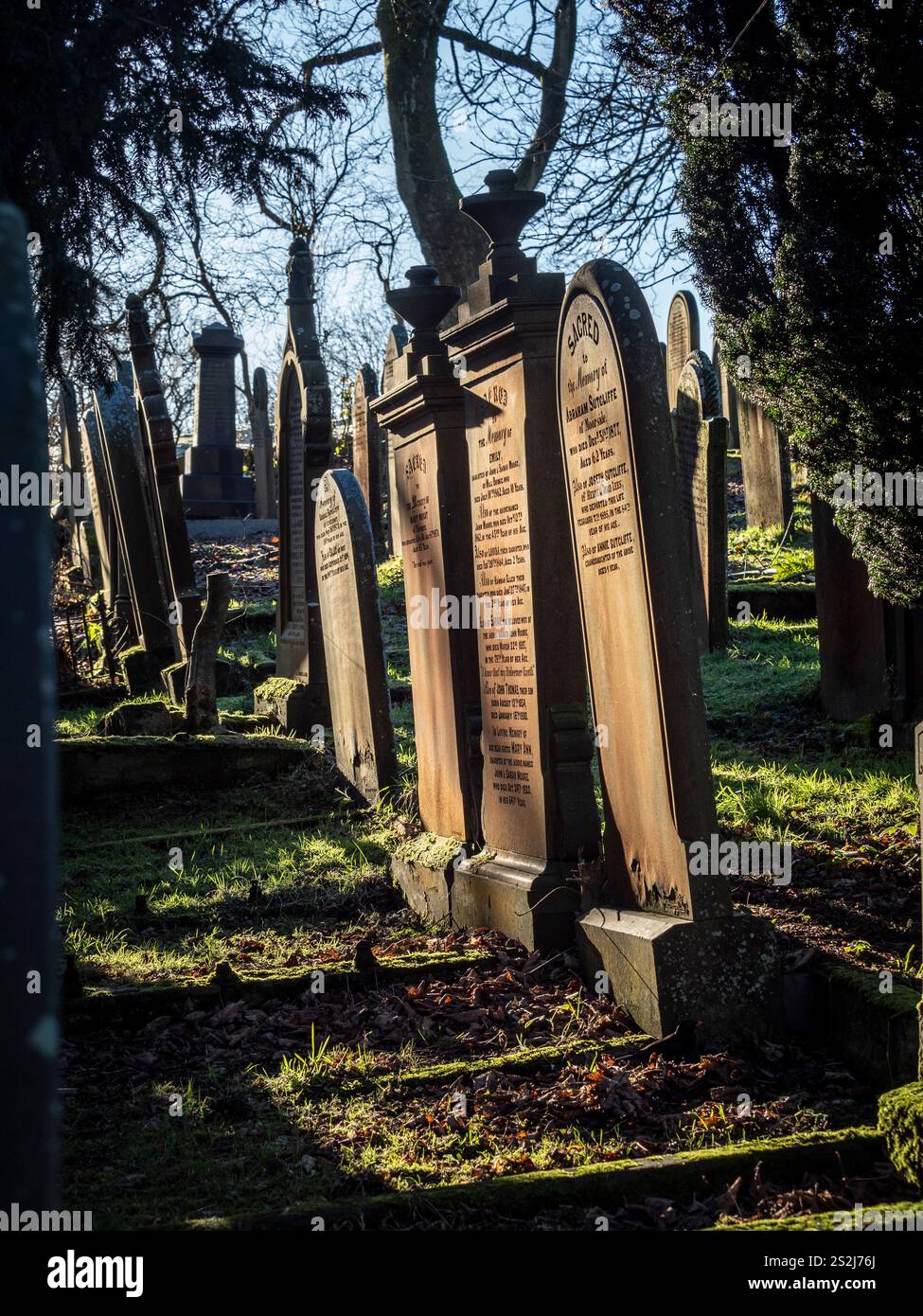 Grabsteine auf dem sonnendurchfluteten Friedhof der St. Michael All Angels Church in Haworth, Bronte Country, West Yorkshire. UK Stockfoto