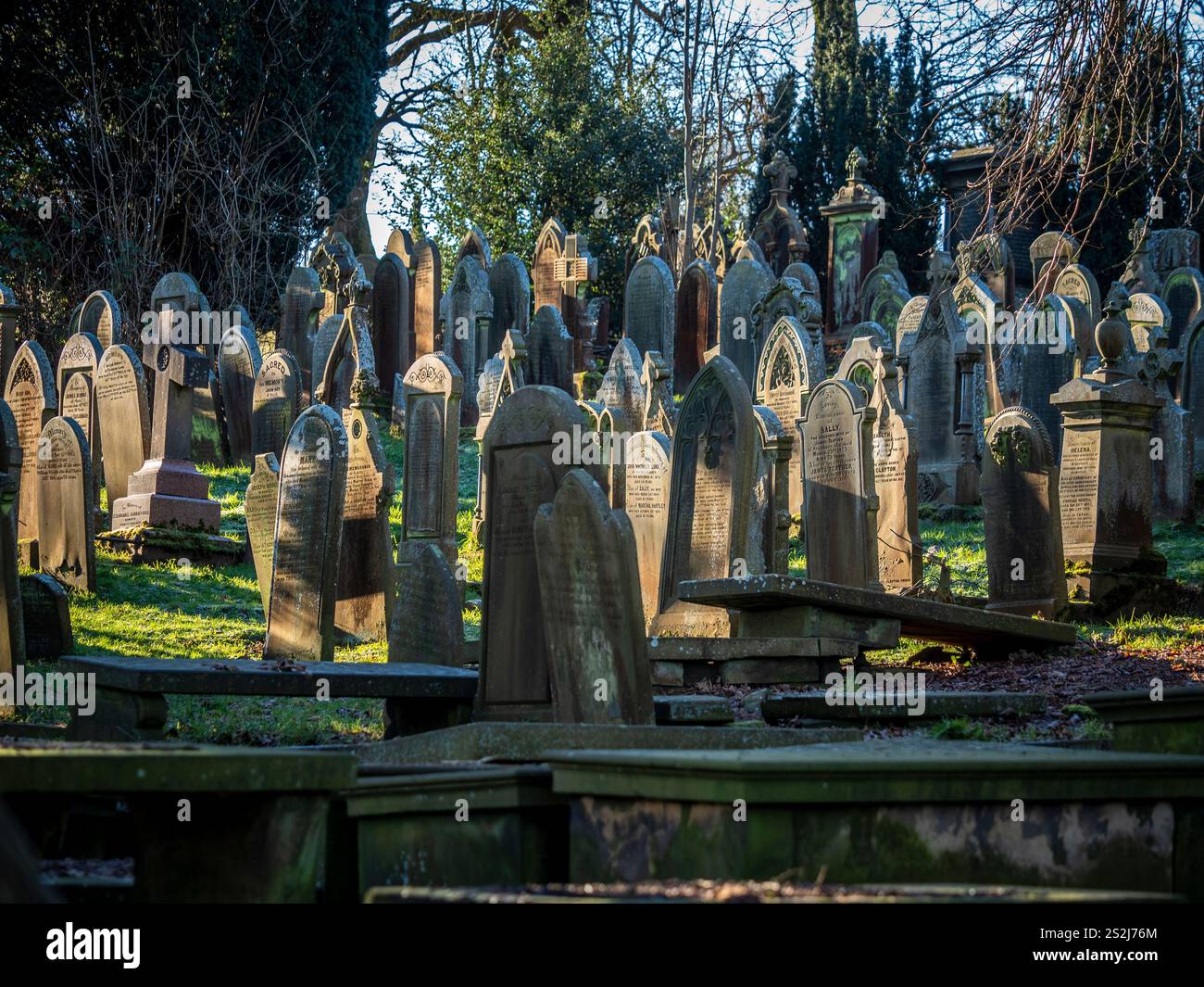 Grabsteine auf dem sonnendurchfluteten Friedhof der St. Michael All Angels Church in Haworth, Bronte Country, West Yorkshire. UK Stockfoto