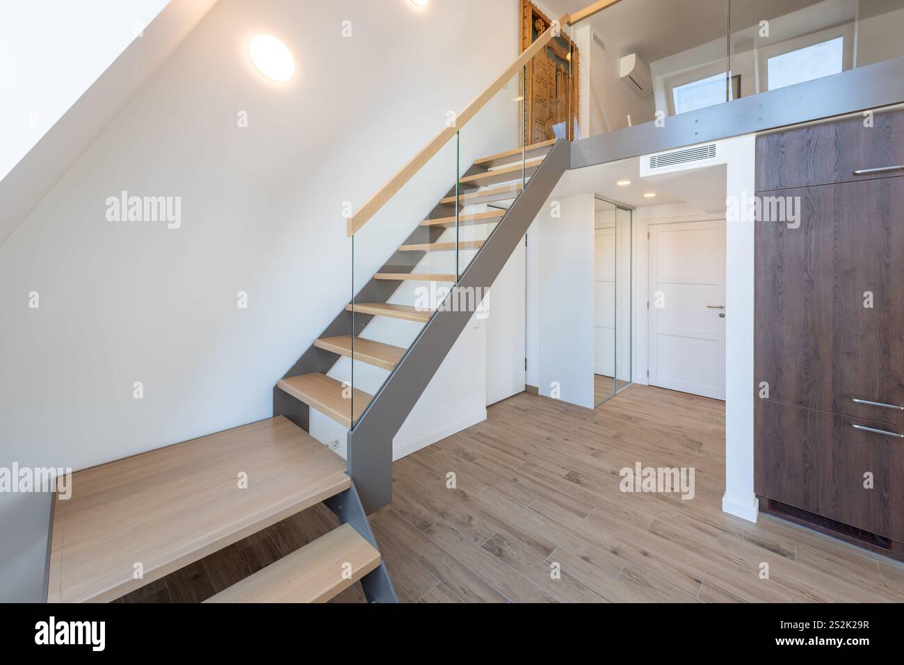 Moderne Holztreppen und Geländer. Oben. Weiße Wände, LED-Licht. Innenraum Zu Hause... Apartment Im Loft-Stil. Weiße Holztür. Innenraum Zu Hause Stockfoto