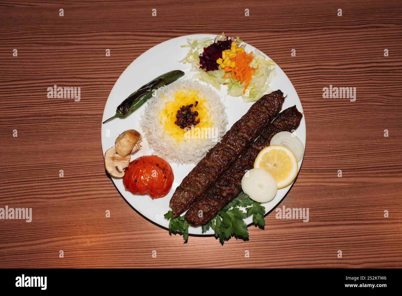 Türkischer Kebab-Teller mit Reis und Salat auf hölzernem Hintergrund. Retro-Flash-Lebensmittelfotografie Stockfoto