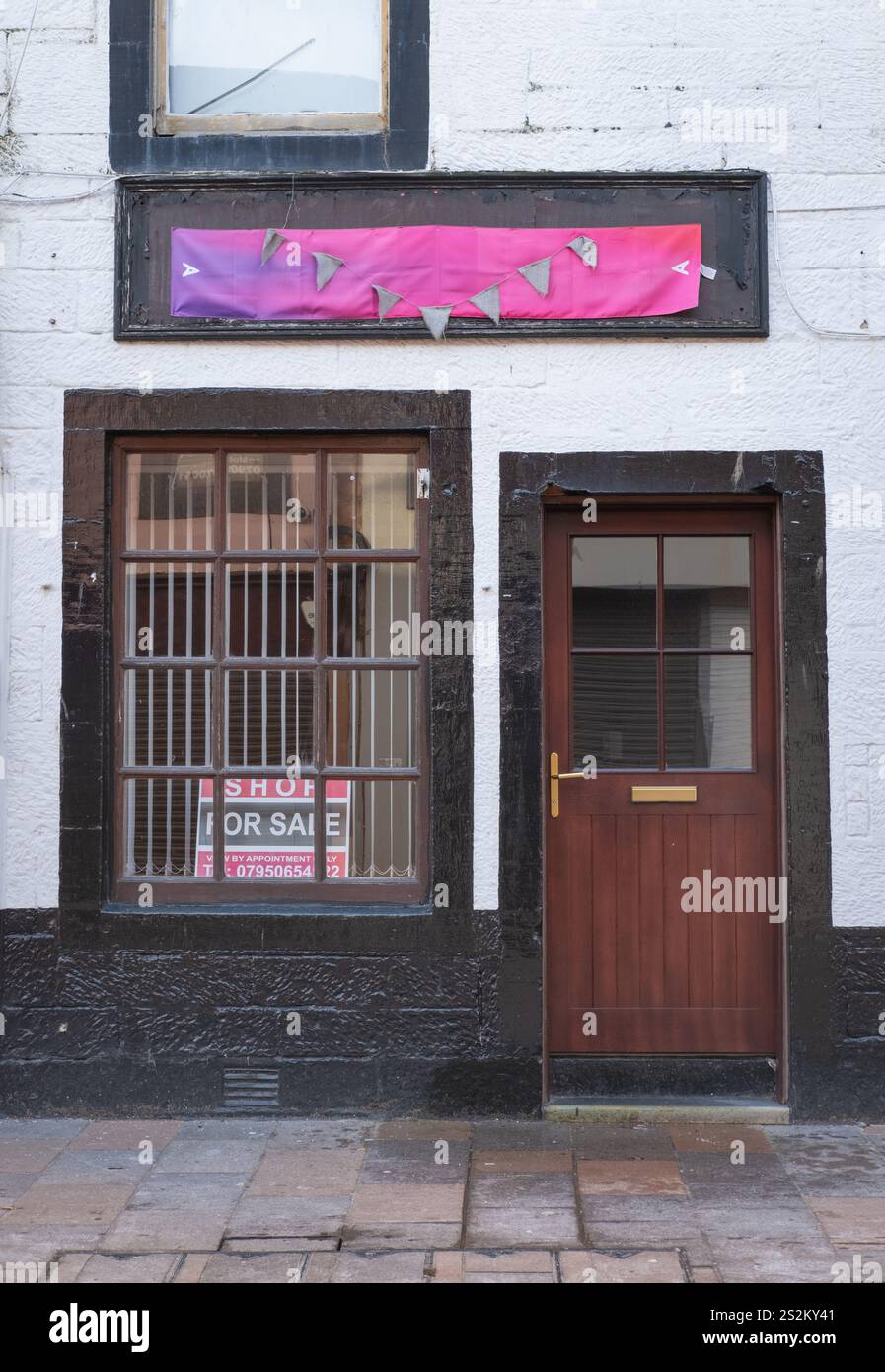 Ein kleines leeres Geschäft mit einem Schild zum Verkauf in Friars Vennel, Dumfries Stadtzentrum, Schottland, ein Beweis für eine schwierige lokale Wirtschaft. Stockfoto