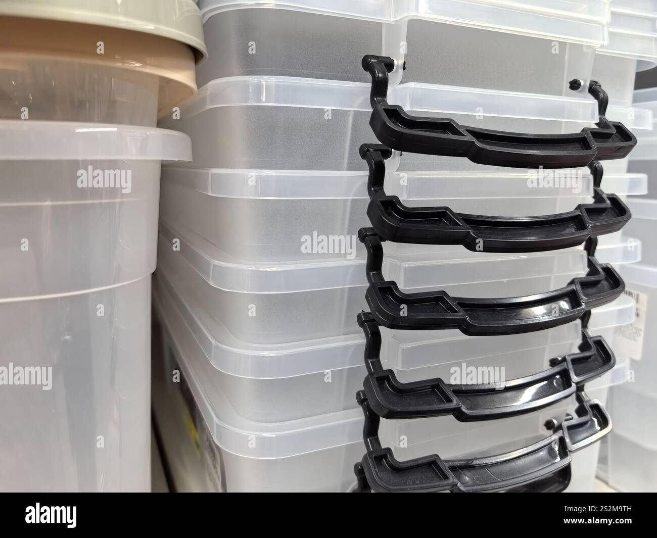 Durchsichtige Kunststoffbehälter stapeln sich ordentlich in einem Lagerbereich und bieten eine organisierte Möglichkeit, Haushaltsgegenstände zu entladen und zu ordnen. Die schwarzen Griffe bieten Stockfoto