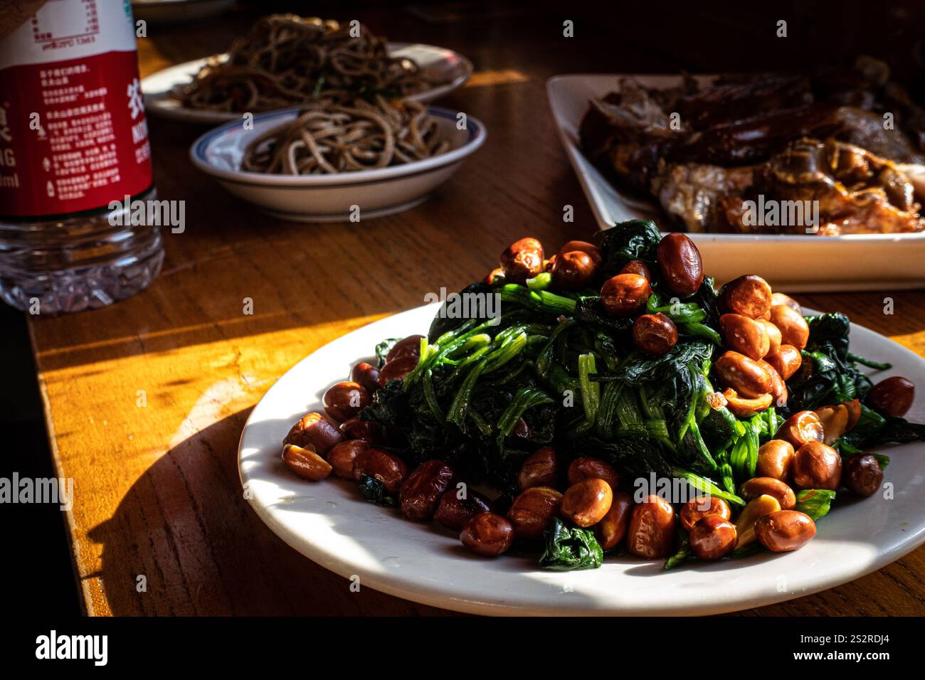 Ein köstlicher Teller mit Speisen wird auf einem stabilen Holztisch neben einer erfrischenden Flasche Wasser für die Versorgung mit Wasser gestellt Stockfoto