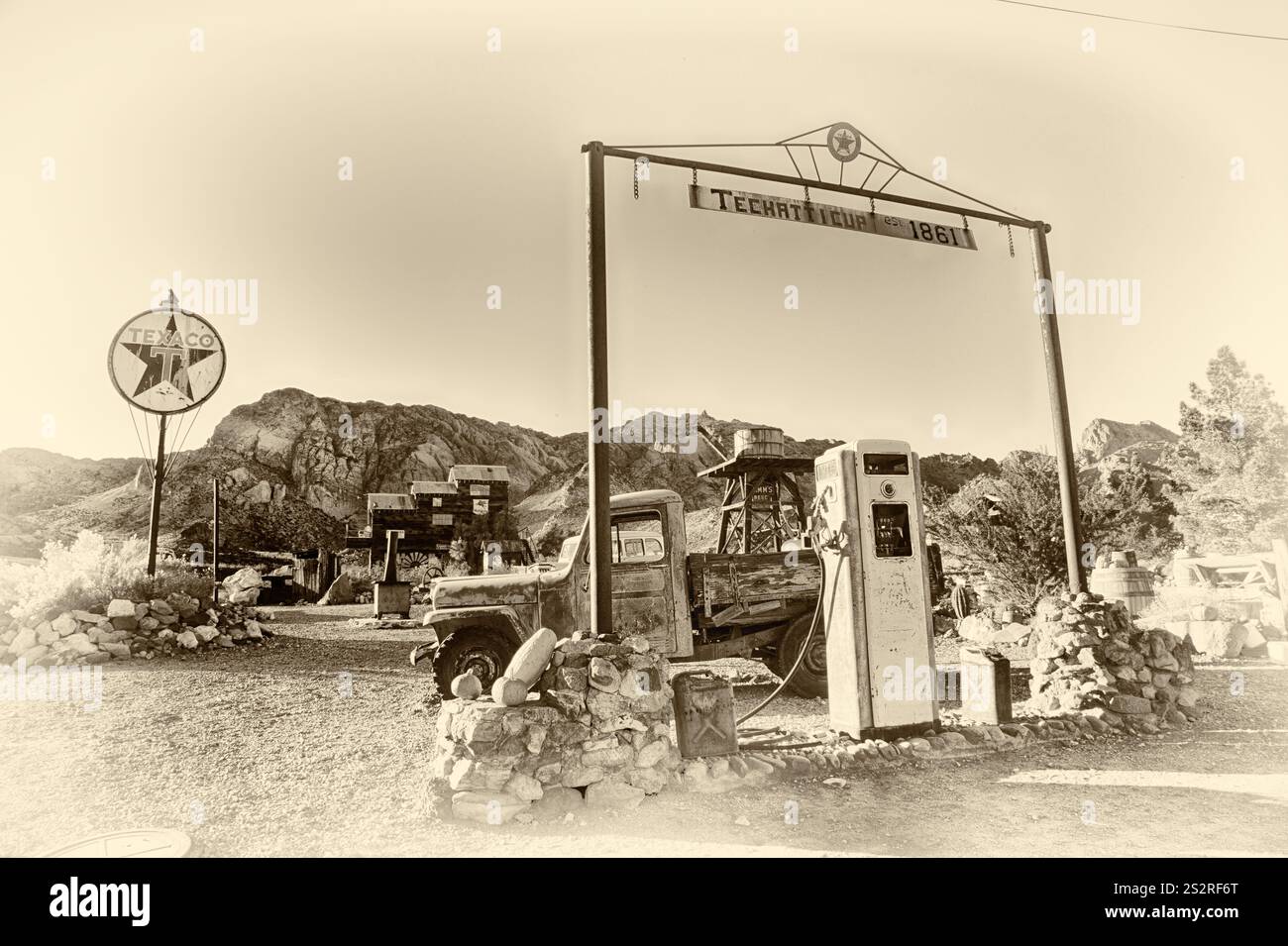 Eine Tankstelle mit einem Schild mit der Aufschrift "T.C.M.C. 1981". Der Bahnhof ist alt und heruntergekommen, vor ihm stehen ein paar Autos. Die Szene ist nostalgisch und so Stockfoto