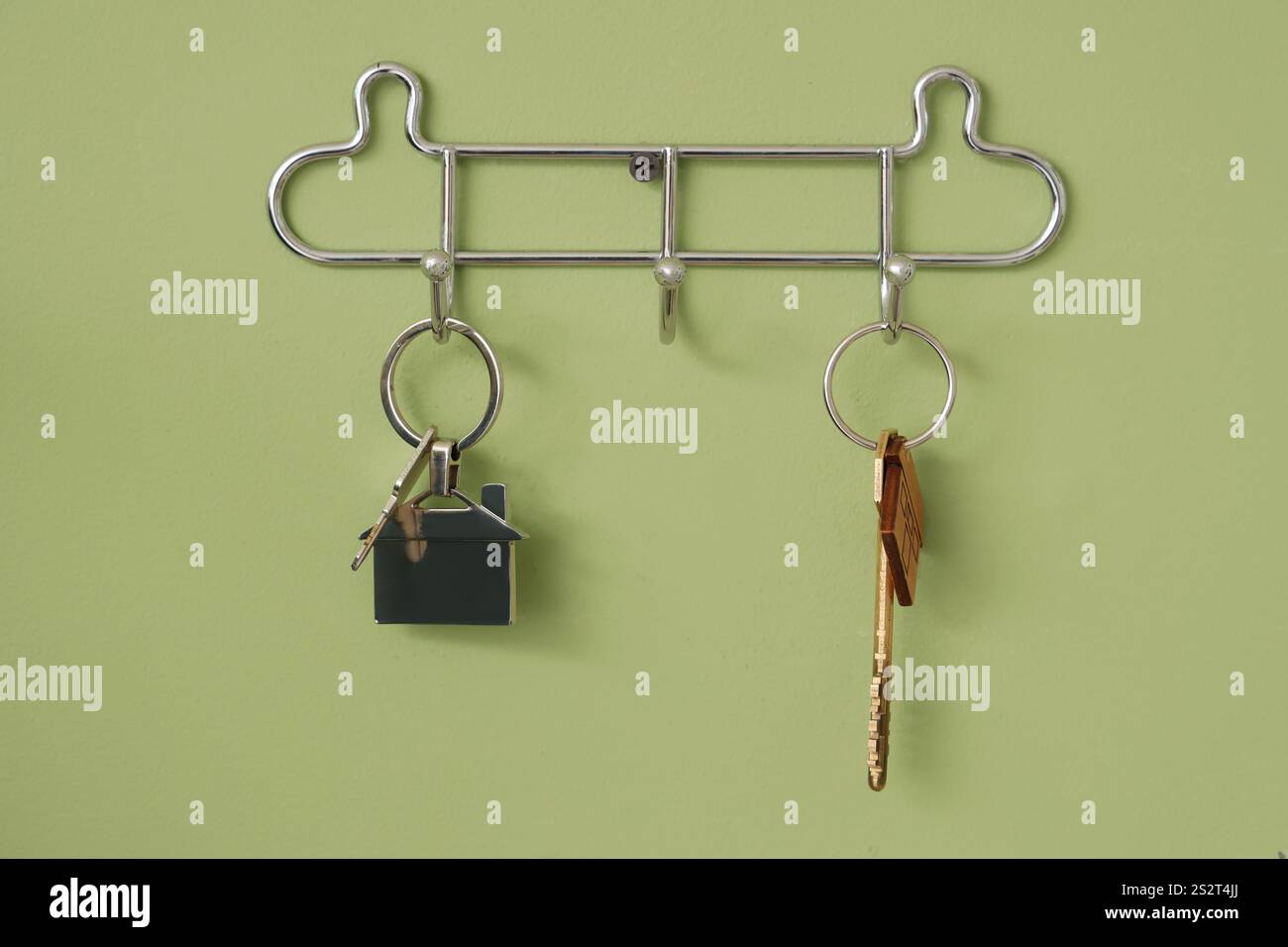 Haken mit Schlüsseln hängen an der grünen Wand, Nahaufnahme Stockfoto