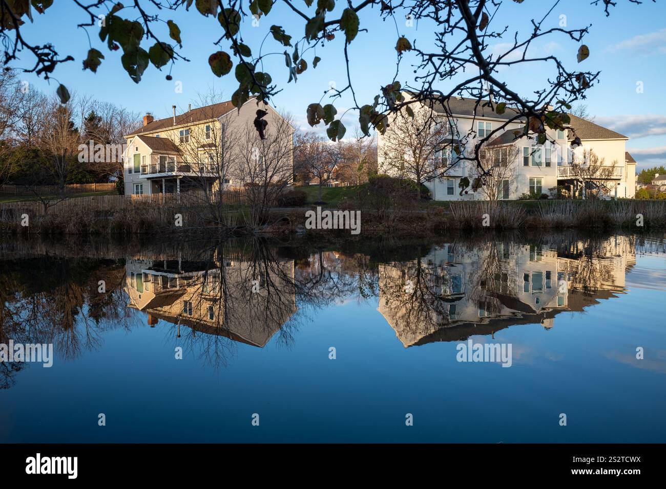 Eine ruhige Szene mit Wohnhäusern im Viertel Ashburn, Virginia, die sich wunderschön in der glasklaren Oberfläche eines stillen Teichs spiegeln und die Stockfoto