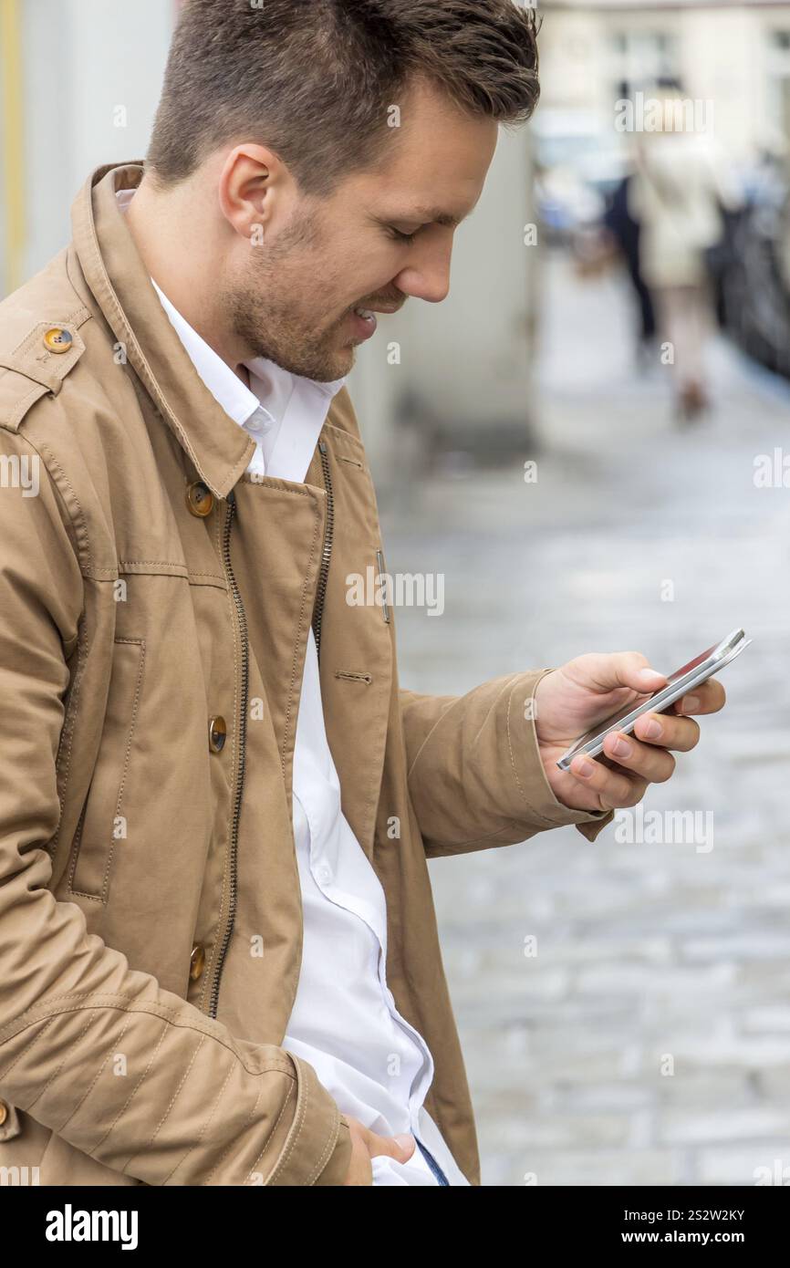 Ein Mann schreibt eine SMS auf seinem Handy. Kommunikation mit einem Smartphone Österreich Stockfoto