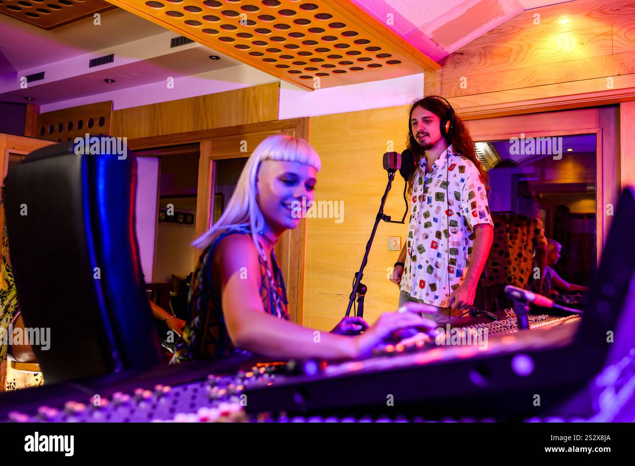 Selektiver Fokus auf einen Sänger, der ein Lied ins Mikrofon singt, während der Produzent seine Stimme in einem Musikstudio aufnimmt. Ein talentierter Künstler ist Singi Stockfoto