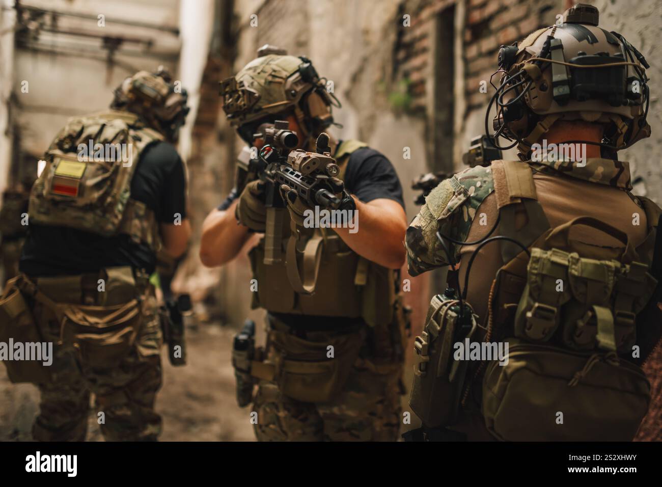 Eine Gruppe tapferer Krieger in militärischen Tarnuniformen, die Gewehre und Waffen halten, während sie eine Mission in einem abgerissenen Gebäude haben. Armee Troo Stockfoto