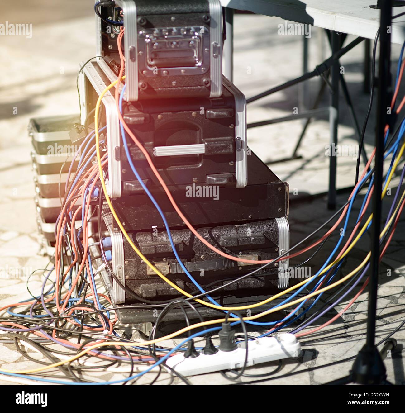 Kompliziertes Netzwerk aus farbenfrohen Kabeln, die gestapelte Audiogeräte miteinander verbinden und die technische Komplexität professioneller Soundsysteme demonstrieren. Stockfoto