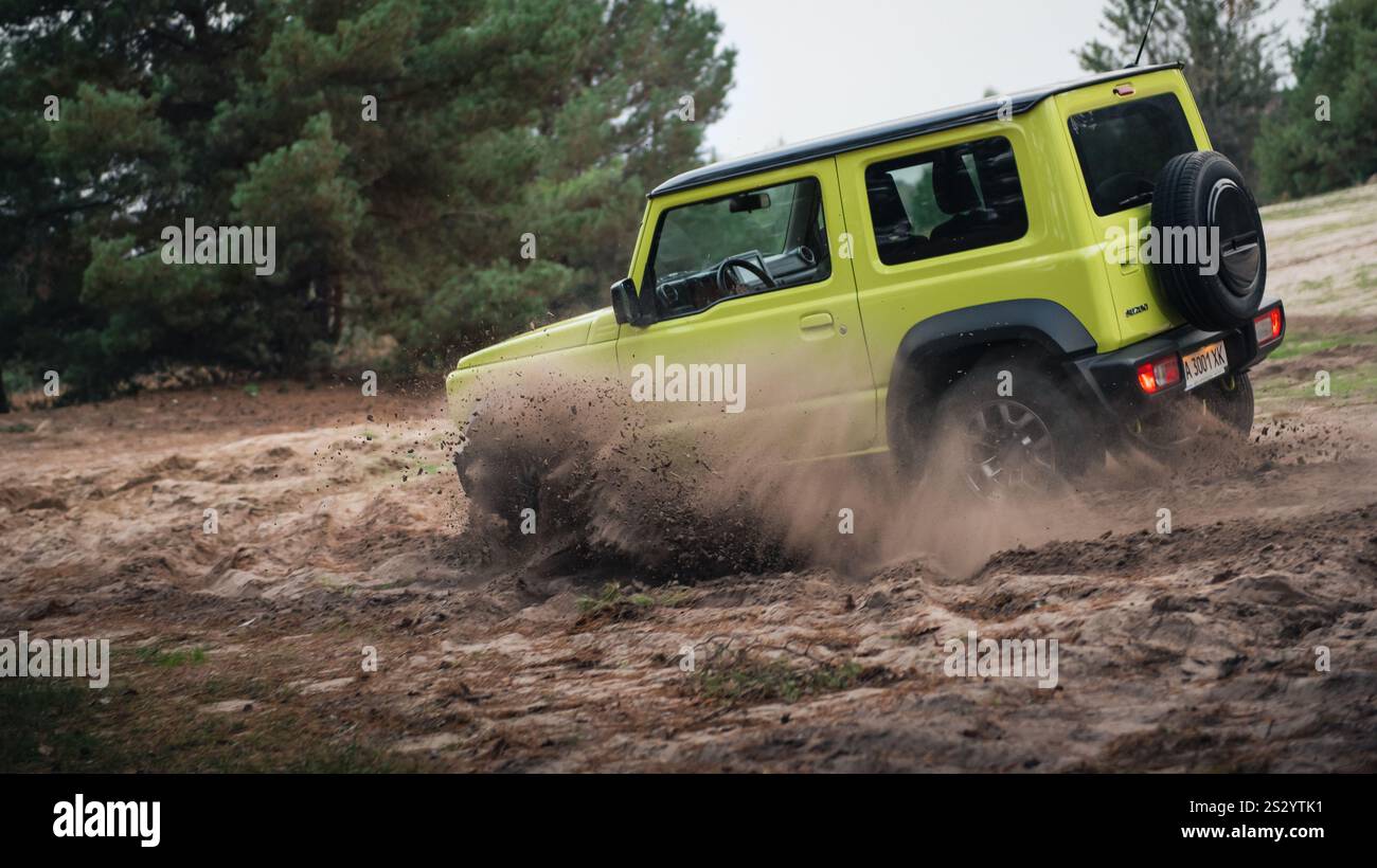 Limettengrün Suzuki Jimny im Wald. Drei Vorderansichten eines Geländewagen-Mini-SUV, der auf Sand im Kiefernwald fährt. Stockfoto