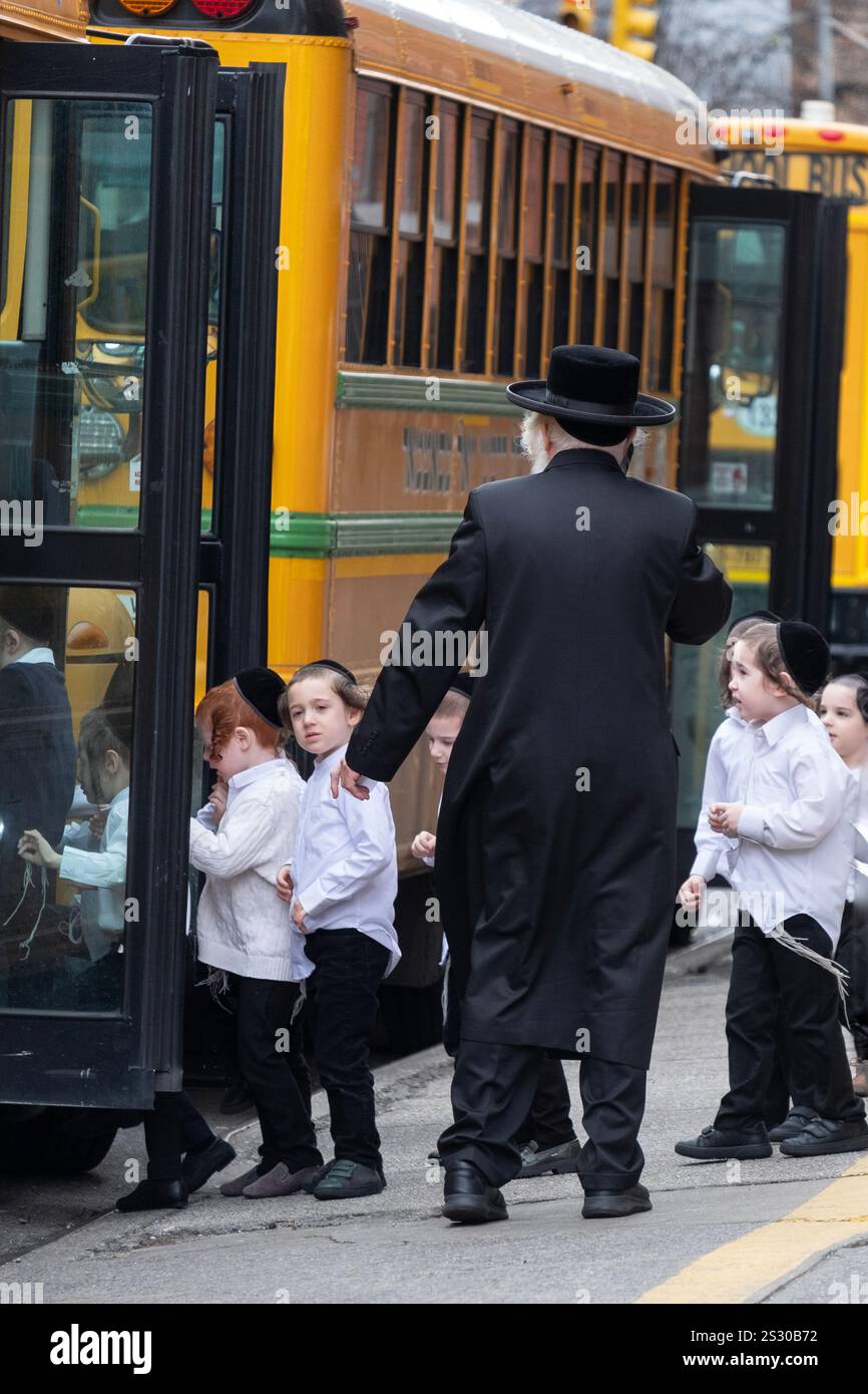 Orthodoxe jüdische Jungs steigen in einen Bus unter den wachsamen Augen eines älteren Rabbiners. In Brooklyn, New York an einem Sonntag. Stockfoto