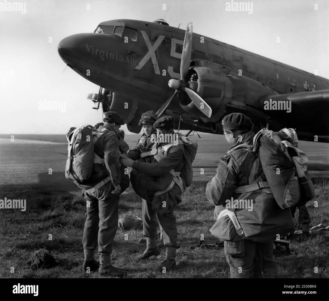 Britische Fallschirmjäger bereiten sich auf einen Douglas Dakota DC-3-Truppenträger vor. Ein Niederflügel-Metallmonoplane mit konventionellem Fahrwerk, angetrieben von zwei Radialkolbenmotoren, war schnell, mit einer guten Reichweite, zuverlässig und konnte von kurzen Landebahnen aus fahren. Während des Zweiten Weltkriegs wurden mehr als 10.000 US-Militärversionen der DC-3 gebaut, wobei die Streitkräfte vieler Länder die DC-3 und ihre militärischen Varianten für den Transport von Truppen, Fracht und Verwundeten verwendeten Stockfoto