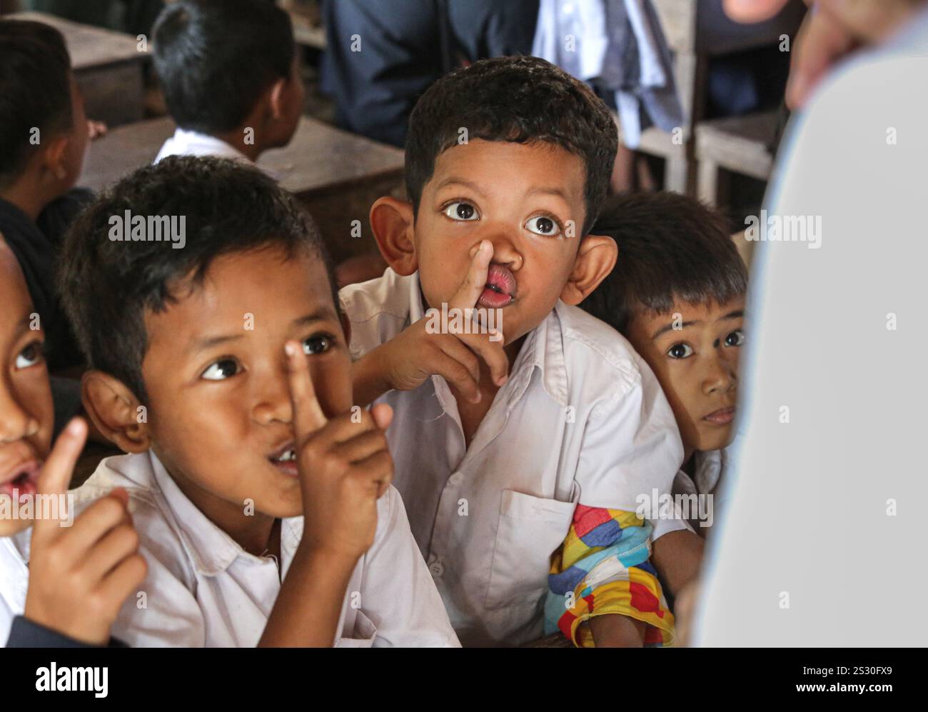 Provinz Kandal, Kambodscha. Januar 2025: Schüler machen das „shh“-Zeichen, um den Unterricht zum Schweigen zu bringen. Zurück zur Schule für Khmer-Kinder in Phnom Penh Vororten, später als in anderen südostasiatischen Ländern. Gestern war ein Feiertag, als Kambodschaner am 7. Januar 1979 den Sieg über den Völkermord feierten, mit der Befreiung der Hauptstadt und dem Fall des Pol Pot-Regimes. Obwohl das Land überwiegend buddhistisch ist (93 % bis 97 %), umfassen die „Winterschulferien“ Weihnachten, den kambodschanischen Friedenstag am 29. Dezember, das Internationale Neujahr und den Siegestag. Quelle: Kevin Izorce/Alamy Live News Stockfoto