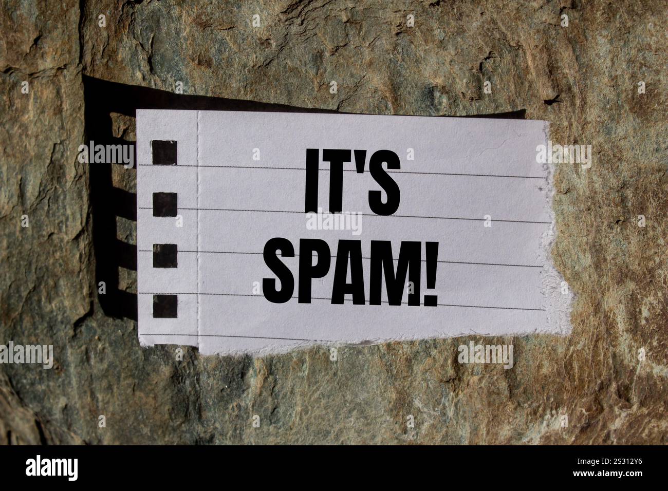 Es ist eine Spam-Nachricht, geschrieben auf zerrissenem Papierstück mit Steinhintergrund. Konzeptionell ist das Spam-Symbol. Kopierbereich. Stockfoto