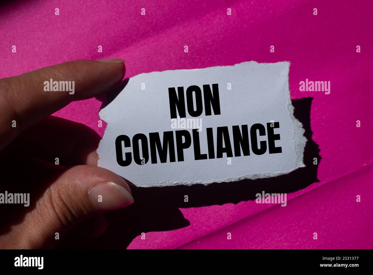 Meldung über Nichteinhaltung auf gerissenem Papierstück mit rosa Hintergrund. Symbol für konzeptionelle Nichteinhaltung. Kopierbereich. Stockfoto