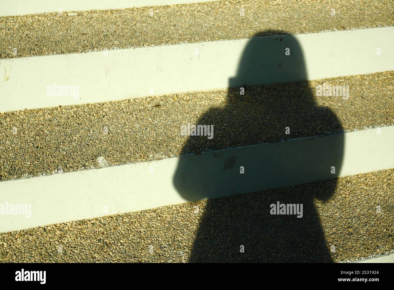 Die Silhouette eines Frauenschattens auf einem Zebraübergang Stockfoto