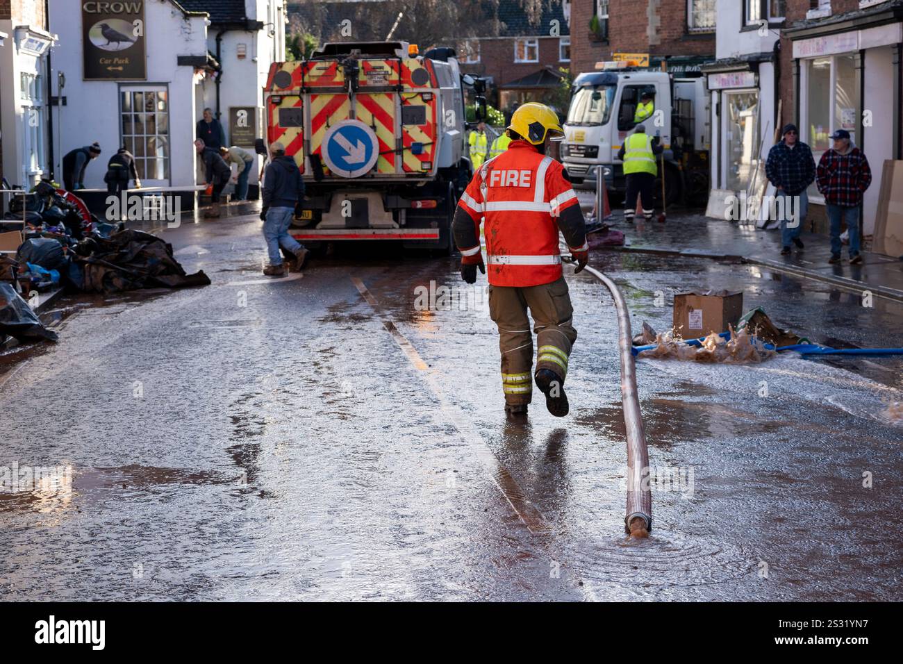 Menschen und Rettungsdienste in der Stadt Tenbury Wells in Worcestershire beseitigen Schlamm und Schlamm nach den Überschwemmungen während des Sturms Bert am 25. November 2024 in Tenbury Wells, Großbritannien. Als starke Regenfälle von Sturm Bert in ganz Großbritannien einschlugen, überflutete Tenbury Wells die Stadt, nachdem der Wasserspiegel am Kyre Brook stieg, was dazu führte, dass eine Mauer an der Market Street einbrach, sodass Hochwasser die Stadt füllen konnte und Grundstücke überschwemmte. Weitere Schäden wurden dadurch verursacht, dass ein Traktor durch die überfluteten Straßen gefahren wurde, was zu einer Welle führte, die die Fenster in lokalen Unternehmen zerbrach. Stockfoto