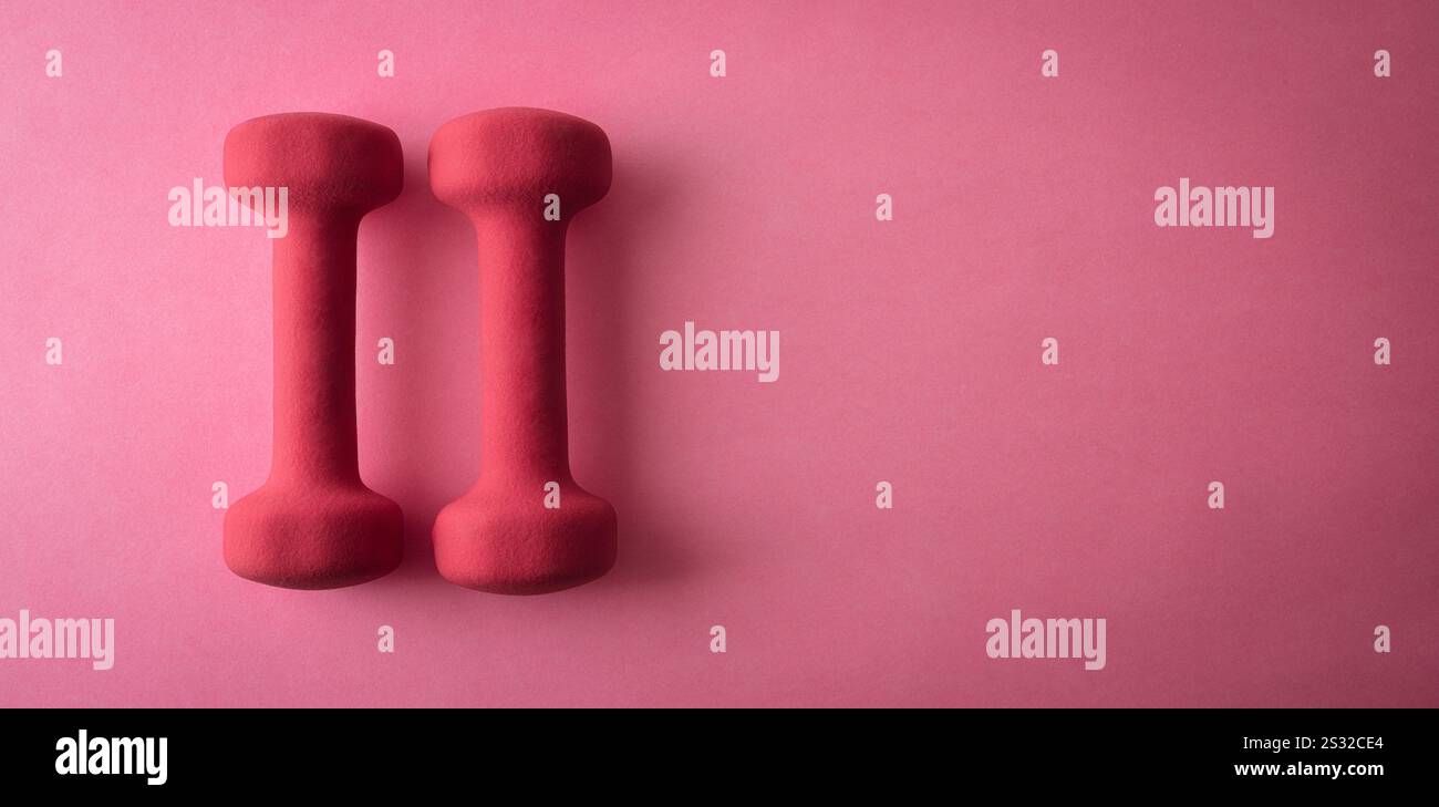 Set aus einem Paar rosa Neopren-Kurzhanteln isoliert auf rosa Hintergrund. Draufsicht. Stockfoto