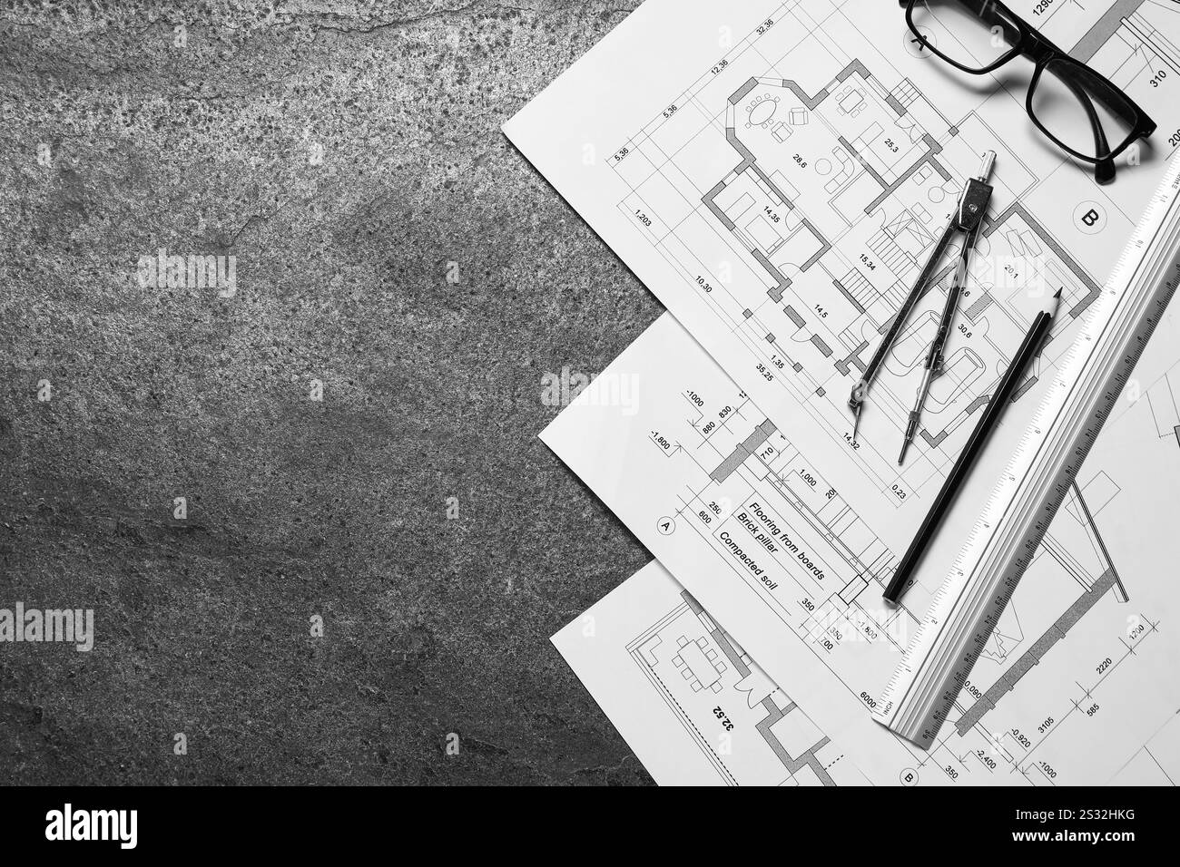 Verschiedene Architekturzeichnungen, Lineal, Trennwand, Bleistift und Gläser auf grauem, strukturiertem Tisch, flache Lagen. Leerzeichen für Text Stockfoto