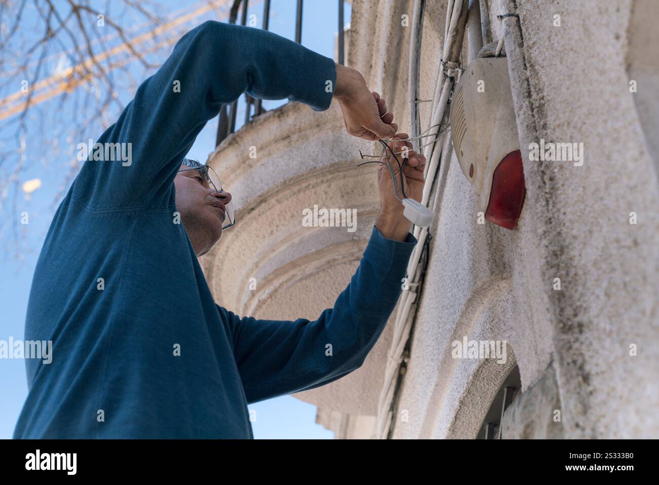 Elektrotechniker, der photoelektrische Zellen an der Fassade eines Hauses installiert. Stockfoto