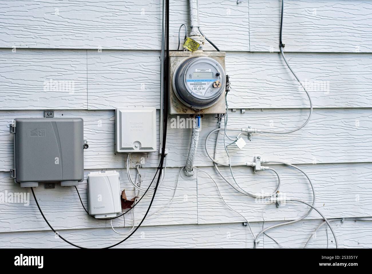 Elektrische, Kabel- und Telefoneingänge an der Außenseite eines aluminiumseitigen Hauses Stockfoto